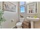 This half bathroom features rustic decor, a pedestal sink, a window, and an artistic horse wall hanging at 20846 E Longwood Dr, Queen Creek, AZ 85142