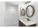 Clean bathroom with single sink vanity and round mirror, adjacent to an open doorway at 21320 N 56Th St # 2005, Phoenix, AZ 85054