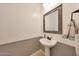 Clean powder room featuring a pedestal sink, framed mirror, and beadboard paneling at 27255 N 81St Ln, Peoria, AZ 85383