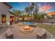 Backyard firepit surrounded by seat walls, near a pool and lush landscaping at dusk at 2876 E Cherrywood Pl, Chandler, AZ 85249