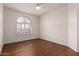 Bright bedroom featuring wood floors, white trim and walls, and a large arched window at 3110 E Desert Flower Ln, Phoenix, AZ 85048