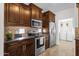 Kitchen features dark wood cabinets, stainless steel appliances, and tile backsplash with adjacent laundry room at 3236 E Chandler Blvd # 2057, Phoenix, AZ 85048