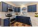 Well-lit kitchen featuring navy blue cabinets, granite counters and stainless steel appliances at 4728 E Swilling Rd, Phoenix, AZ 85050