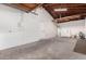 Unfinished garage with exposed wood beam ceiling and white painted walls and doors at 5716 W Hazelwood St, Phoenix, AZ 85031