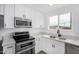 Well-lit kitchen with white cabinets, stainless steel appliances and gray wood-look floors at 5716 W Hazelwood St, Phoenix, AZ 85031