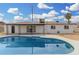 Inviting backyard pool with a covered patio, set against a charming white brick home under a clear, blue sky at 5716 W Hazelwood St, Phoenix, AZ 85031