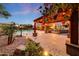 View of the covered cabana with ambient lighting, overlooking the pool and lush backyard landscaping at twilight at 6221 S 45Th Gln, Laveen, AZ 85339