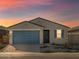 Charming single-story home with a blue garage door, stone accents, and desert landscaping at sunset at 8613 W Warner St, Tolleson, AZ 85353