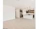 Open-concept living space with light wood floors leading to the kitchen with a central island and stainless appliances at 8613 W Warner St, Tolleson, AZ 85353