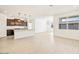 Bright living area with light floors open to a modern kitchen with pendant lighting and a view outside the window at 8613 W Warner St, Tolleson, AZ 85353