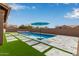 Inviting pool area with a hot tub, lush artificial grass, and stone pavers providing a modern and relaxing outdoor space at 9393 E Hunter Ct, Scottsdale, AZ 85262