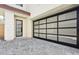 Two-car garage with modern glass panel door and stone-accented entryway with black framed door at 1 Easy St # 11, Carefree, AZ 85377