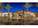 Beautifully lit clubhouse with palm trees, showcasing its elegant architecture and inviting atmosphere at night at 12915 W Lone Tree Trl, Peoria, AZ 85383