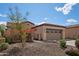 Side view of a tan home with a two-car garage, desert landscaping and a secure gated entrance at 12915 W Lone Tree Trl, Peoria, AZ 85383