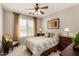 Cozy bedroom showcasing a decorative ceiling fan, accent chair, and bright, sunny windows at 15696 W Roanoke Ave, Goodyear, AZ 85395