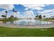 Picturesque pond with water fountains, surrounded by lush landscaping and palm trees at 15696 W Roanoke Ave, Goodyear, AZ 85395