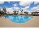 Beautiful community pool with plenty of seating surrounded by palm trees under a bright blue partially cloudy sky at 15696 W Roanoke Ave, Goodyear, AZ 85395