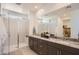 Modern bathroom with double sinks, dark wood cabinets, a large mirror, and a glass-enclosed shower at 15815 W Kendall St, Goodyear, AZ 85338