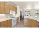 Well-lit kitchen featuring light wood cabinets, white appliances, tile flooring, and a view into an adjacent living space at 16100 W Galleria Ln, Surprise, AZ 85374