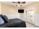 Bedroom showcasing a ceiling fan, mounted TV, and double doors leading to a balcony at 17975 W Agave Rd, Goodyear, AZ 85338