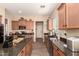 Open kitchen featuring granite countertops, wood cabinets, stainless steel appliances, and wood-look tile flooring at 17975 W Agave Rd, Goodyear, AZ 85338