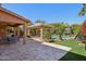 An outdoor living space with a covered patio with bar seating, pool, grassy area, and lush landscaping at 18504 W Maui Ln, Surprise, AZ 85388