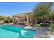 An inviting backyard featuring a sparkling pool, covered patio with a fire pit, and lush green grass at 18504 W Maui Ln, Surprise, AZ 85388