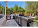 A luxurious outdoor kitchen featuring stainless steel appliances, granite countertops, and a picturesque backyard with mature trees at 18504 W Maui Ln, Surprise, AZ 85388