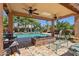 A stunning outdoor living space with a covered patio, ceiling fans, a cozy fire pit, and a sparkling swimming pool at 18504 W Maui Ln, Surprise, AZ 85388