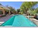 An inviting swimming pool featuring a tranquil waterfall feature, lush landscaping, and a covered patio with a fire pit at 18504 W Maui Ln, Surprise, AZ 85388