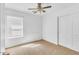 Cozy bedroom features a ceiling fan, large window, and closet with sliding doors at 21655 N Davis Way, Maricopa, AZ 85138