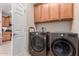 Laundry room with wooden cabinets and modern washer and dryer at 26288 W Horsham Ct, Buckeye, AZ 85396