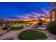 Stunning backyard with putting green, fire pit, tennis court and desert landscaping at dusk at 27632 N 68Th Pl, Scottsdale, AZ 85266