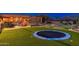 Expansive backyard with a trampoline, putting green, mature landscaping, and luxury home with outdoor living spaces at 27632 N 68Th Pl, Scottsdale, AZ 85266