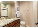 Bathroom with a granite countertop, wooden cabinets, decorative mirror, and a toilet at 27632 N 68Th Pl, Scottsdale, AZ 85266