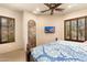 Cozy bedroom with light walls, wood trim, TV, ceiling fan, and window with wood shutters at 27632 N 68Th Pl, Scottsdale, AZ 85266