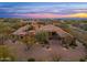 Expansive home with a porte cochere entry, lush desert landscaping, and vibrant sunset skies at 27632 N 68Th Pl, Scottsdale, AZ 85266