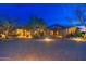 Estate home showcasing a circular driveway, porte cochere, and lush desert landscaping with accent lighting at 27632 N 68Th Pl, Scottsdale, AZ 85266