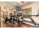 Modern home gym featuring a treadmill, spinning bikes, and a wall-mounted mirror and TV at 27632 N 68Th Pl, Scottsdale, AZ 85266