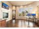 Bright living room with curved windows, a fireplace, and wood floors provides a cozy yet open space at 27632 N 68Th Pl, Scottsdale, AZ 85266