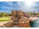 Resort-style pool featuring a rock waterfall, a putting green, and a lush, landscaped backyard under a beautiful sky at 27632 N 68Th Pl, Scottsdale, AZ 85266