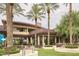 Exterior view of clubhouse with outdoor seating area, lush green landscaping, and palm trees at 30110 N 129Th Gln, Peoria, AZ 85383