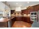 Gourmet kitchen featuring dark wood cabinets, terracotta floors and stainless steel appliances at 30110 N 129Th Gln, Peoria, AZ 85383