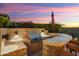 An outdoor grill and kitchen area feature bar seating and desert landscaping at twilight at 30110 N 129Th Gln, Peoria, AZ 85383