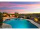 An inviting backyard pool and fire pit area are showcased against a pink sunset at 30110 N 129Th Gln, Peoria, AZ 85383