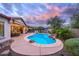 Twilight view of a backyard featuring a pool, rock waterfall, patio and built in barbeque at 30550 N 125Th Dr, Peoria, AZ 85383