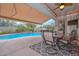 Inviting covered patio with a dining set offers a view of the sparkling pool and lush landscaping at 30550 N 125Th Dr, Peoria, AZ 85383