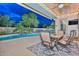 Covered patio with a dining set is perfectly positioned for relaxing evenings by the sparkling pool and waterfall feature at 30550 N 125Th Dr, Peoria, AZ 85383