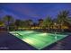 A large, inviting swimming pool illuminated at dusk, surrounded by palm trees and lounge chairs at 30550 N 125Th Dr, Peoria, AZ 85383