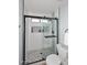 A tiled bathroom with a rainfall shower head, built in storage shelves, a shower seat, and black framed glass door at 4338 E Towne Ln, Gilbert, AZ 85234